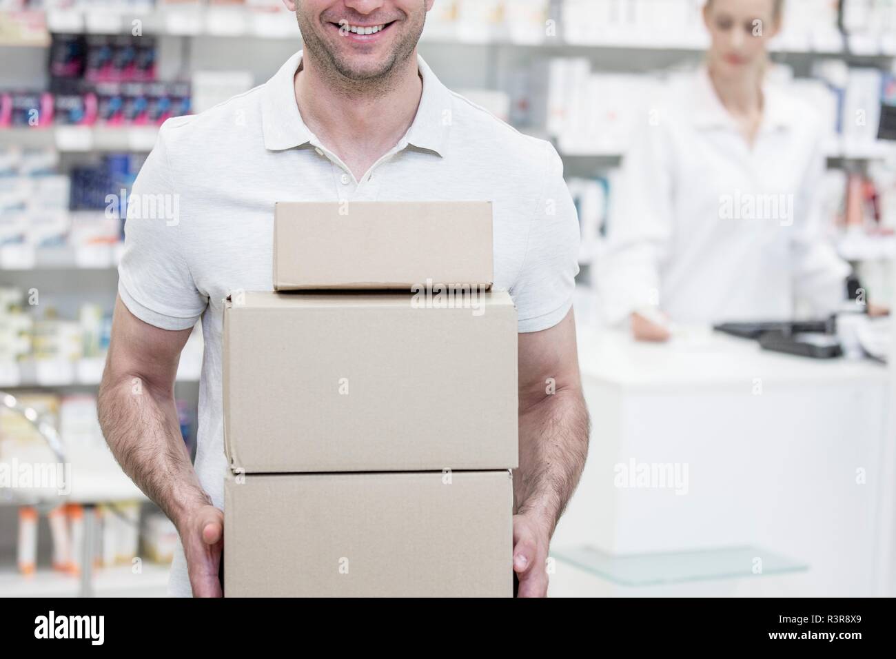 Corriere scatole porta in farmacia con il farmacista in background. Foto Stock