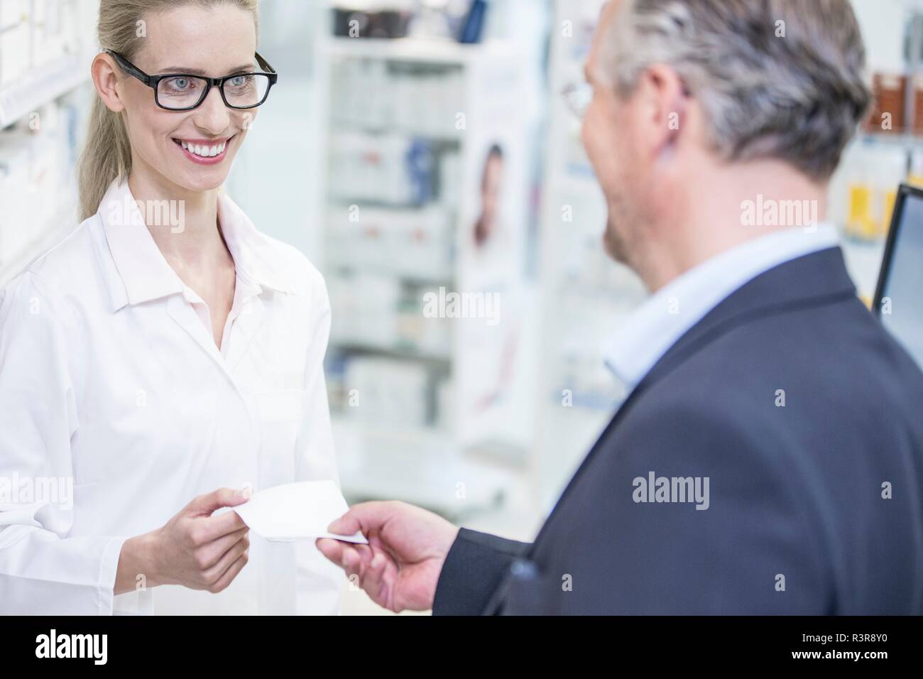Cliente dando la prescrizione al farmacista in farmacia. Foto Stock