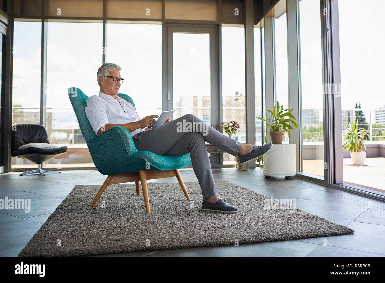Coppia uomo seduto in poltrona a casa utilizzando tablet Foto Stock