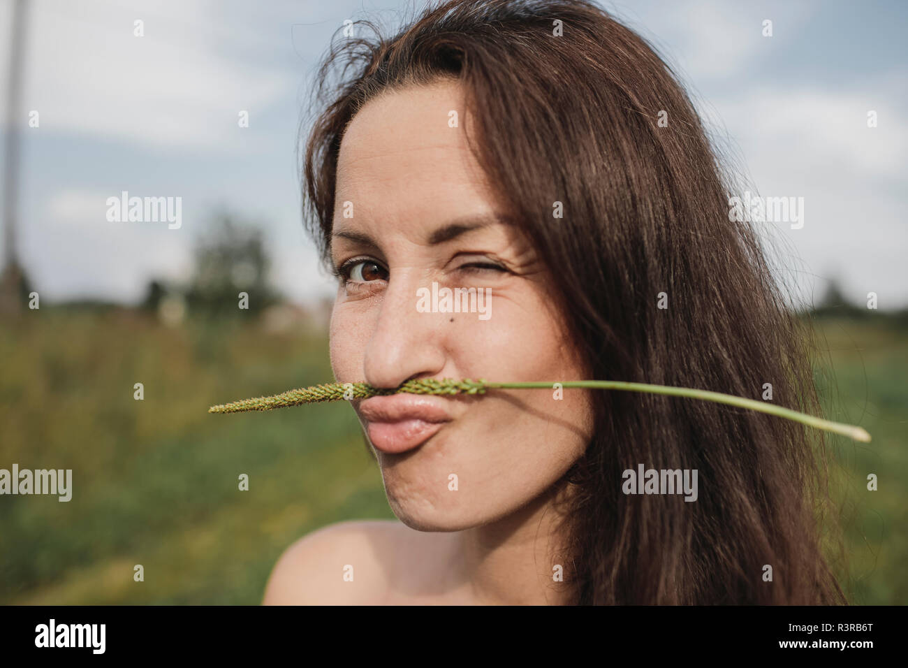Ritratto di donna impianto di bilanciamento levetta sulla sua bocca luccichio Foto Stock