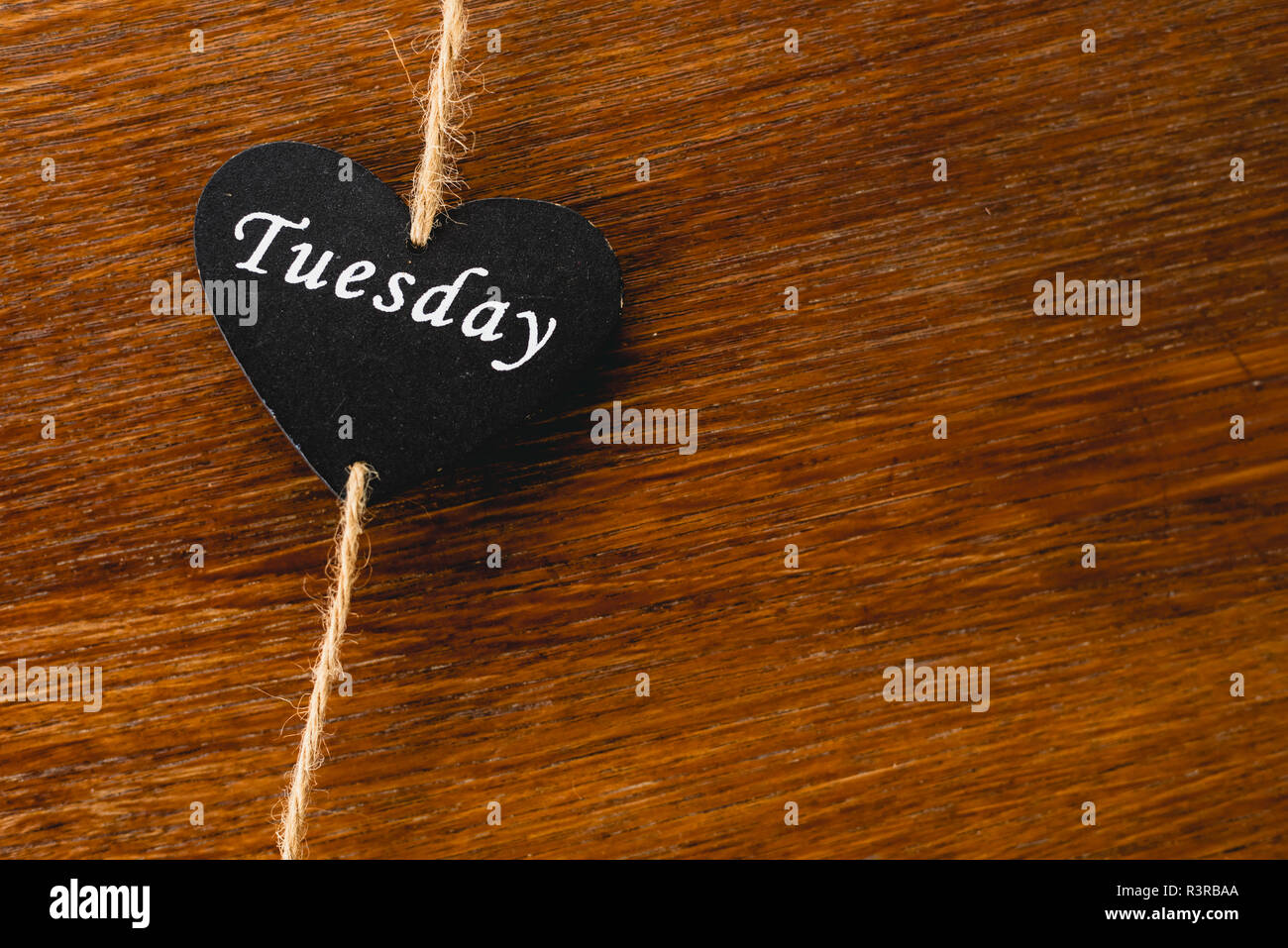 Cuore di legno nero con il giorno della settimana scritto su di esso, Martedì Foto Stock