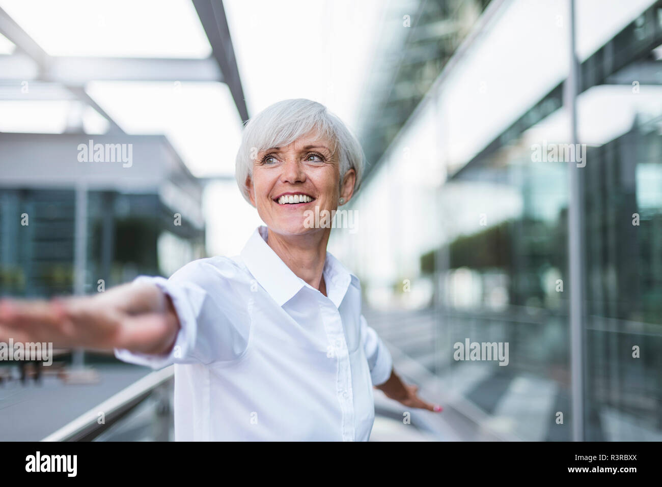 Felice donna senior in città con le braccia tese Foto Stock