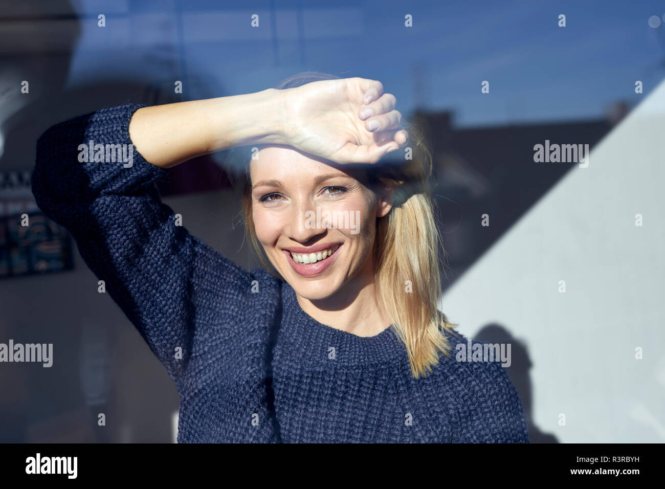 Ritratto di felice donna bionda guardando fuori della finestra Foto Stock