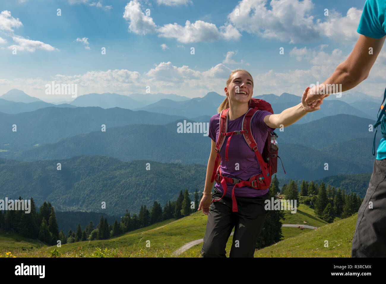 In Germania, in Baviera, vicino Brauneck Lenggries, felice giovane donna escursioni nel paesaggio alpino tenendo la mano del fidanzato Foto Stock