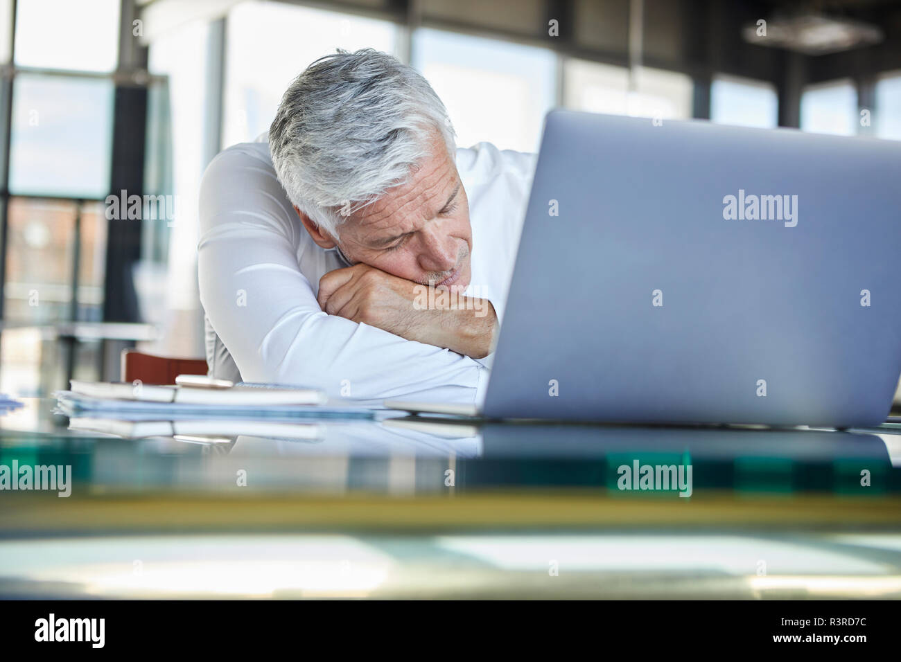 Imprenditore esausto dorme nella parte anteriore del computer portatile Foto Stock