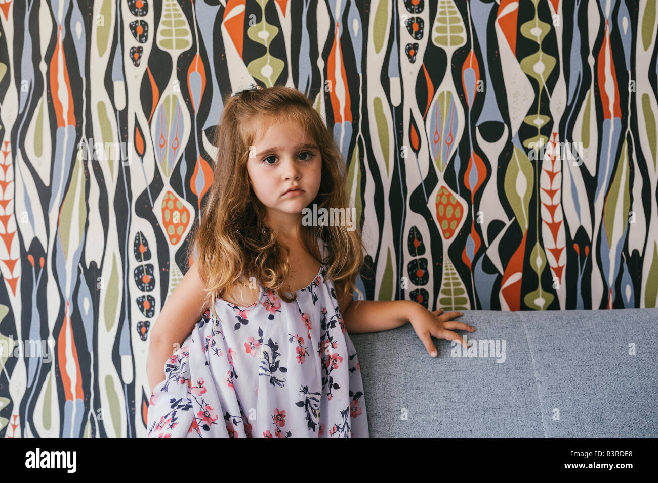 Ritratto di grave bambina sul lettino nella parte anteriore della carta da parati Foto Stock