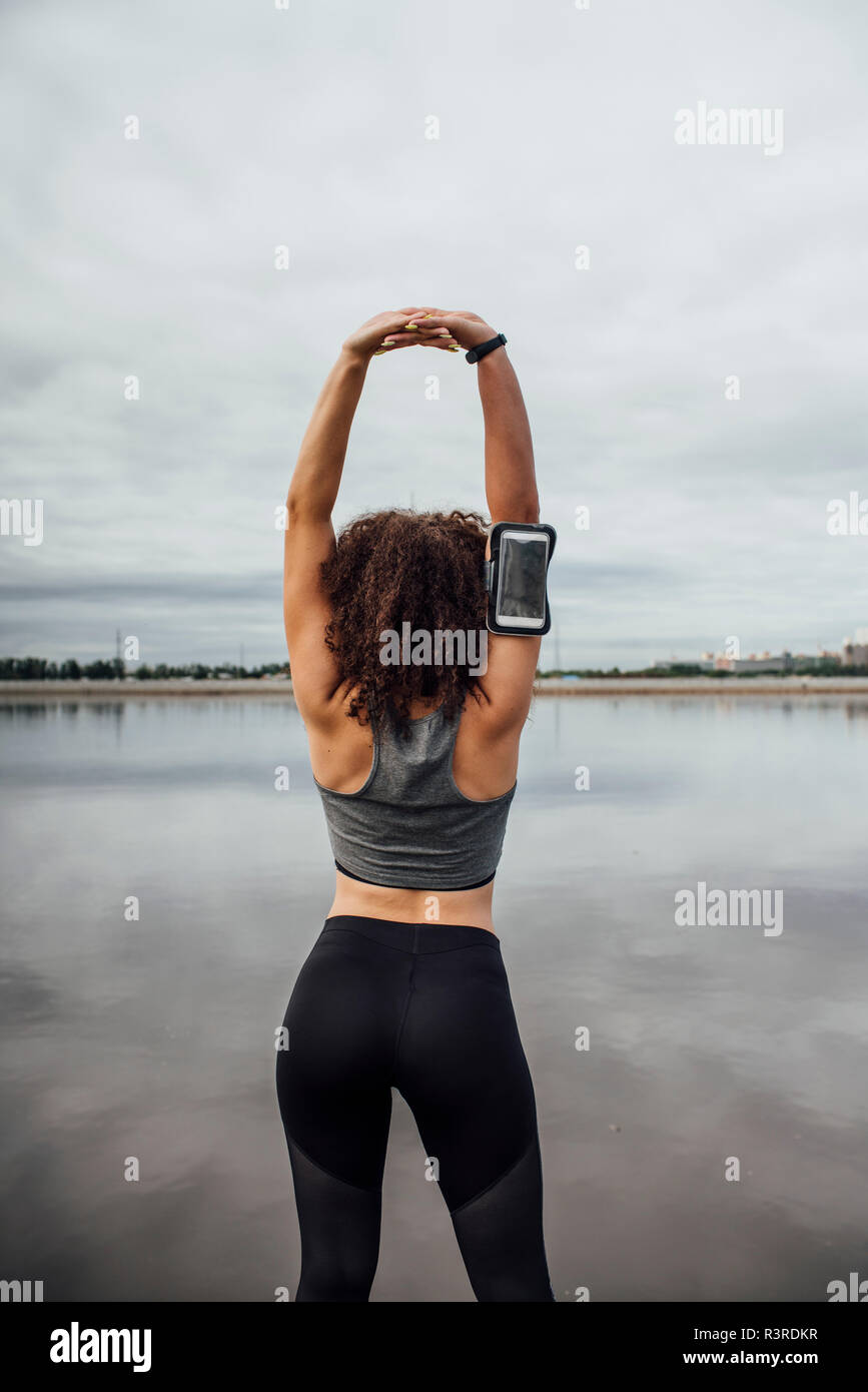 Vista posteriore del giovane donna atletica stretching al Riverside Foto Stock