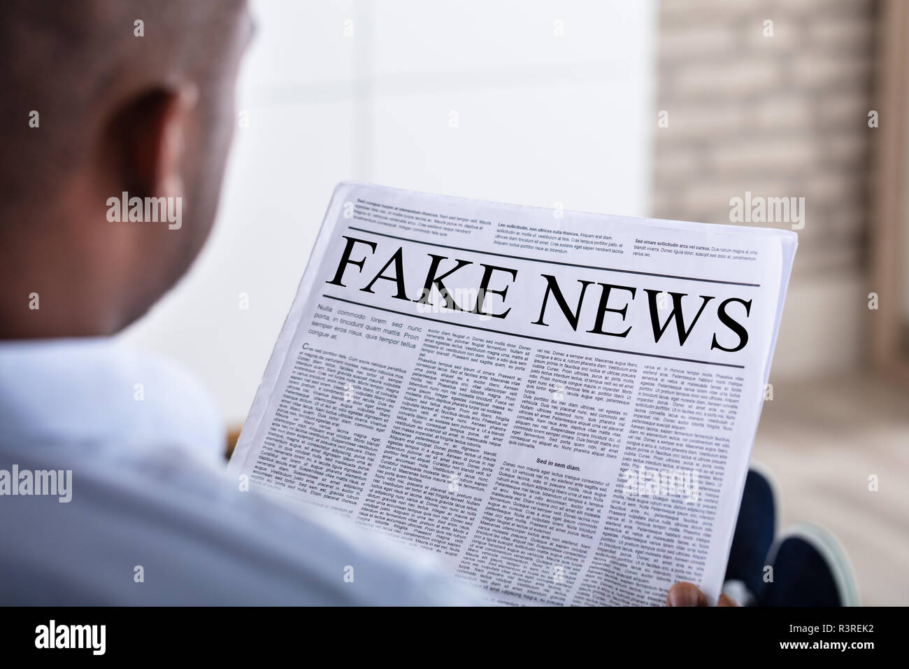 Close-up di un uomo africano lettura notizie false sul giornale Foto Stock