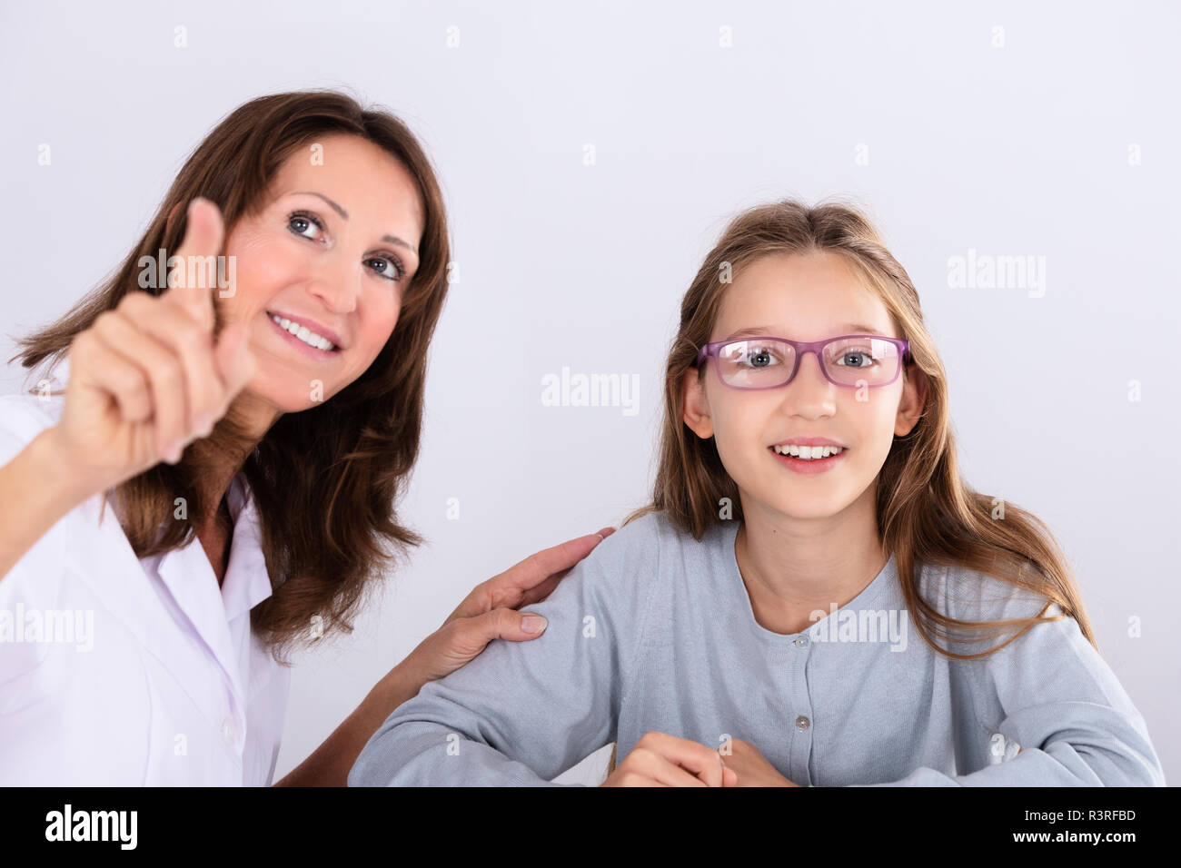 Femmina felice all'ottico optometrista puntare il dito mentre si verifica la visione degli occhi di una ragazza Foto Stock