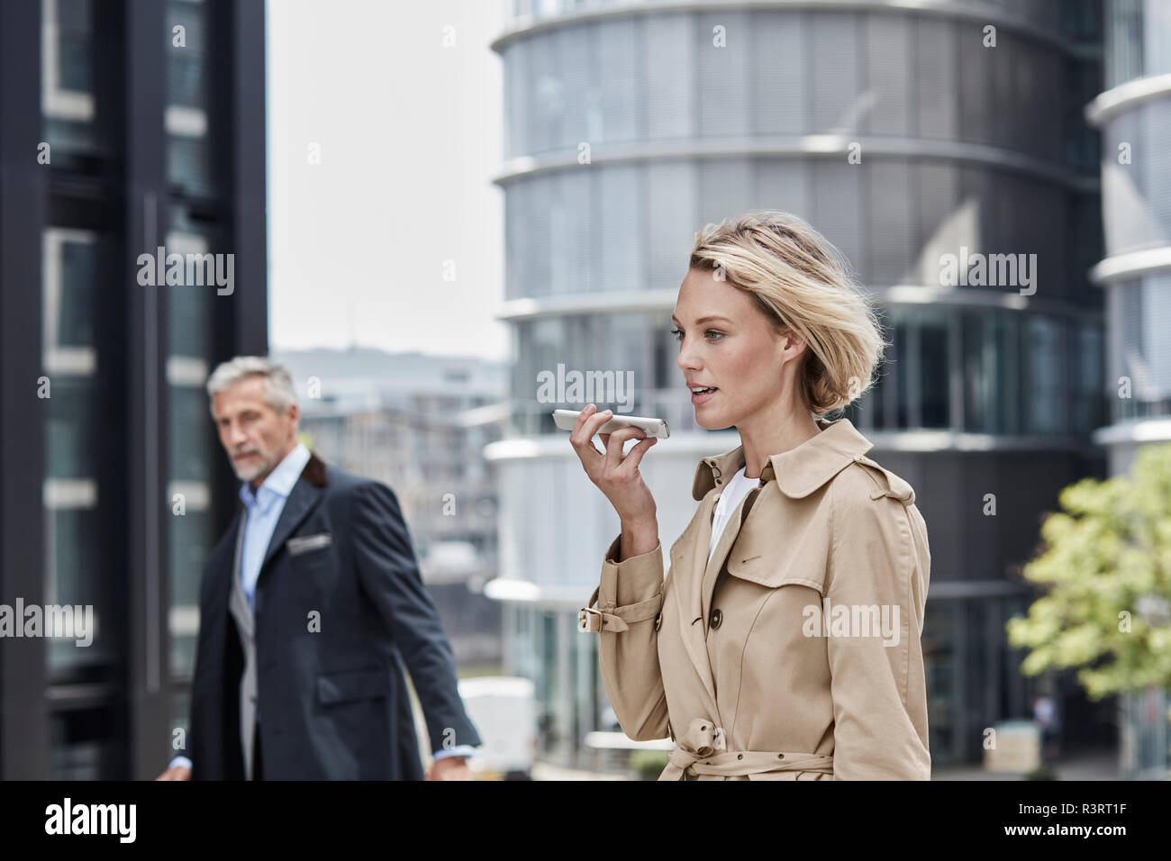 Germania, Duesseldorf, ritratto del biondo imprenditrice indossando il beige trench parlando al telefono cellulare Foto Stock