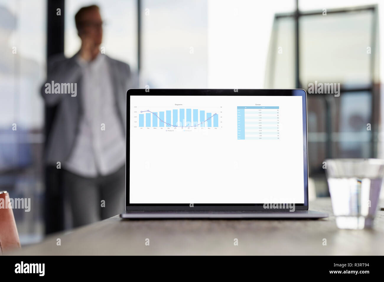 Grafico su schermo laptop sulla scrivania in ufficio con imprenditore in background Foto Stock
