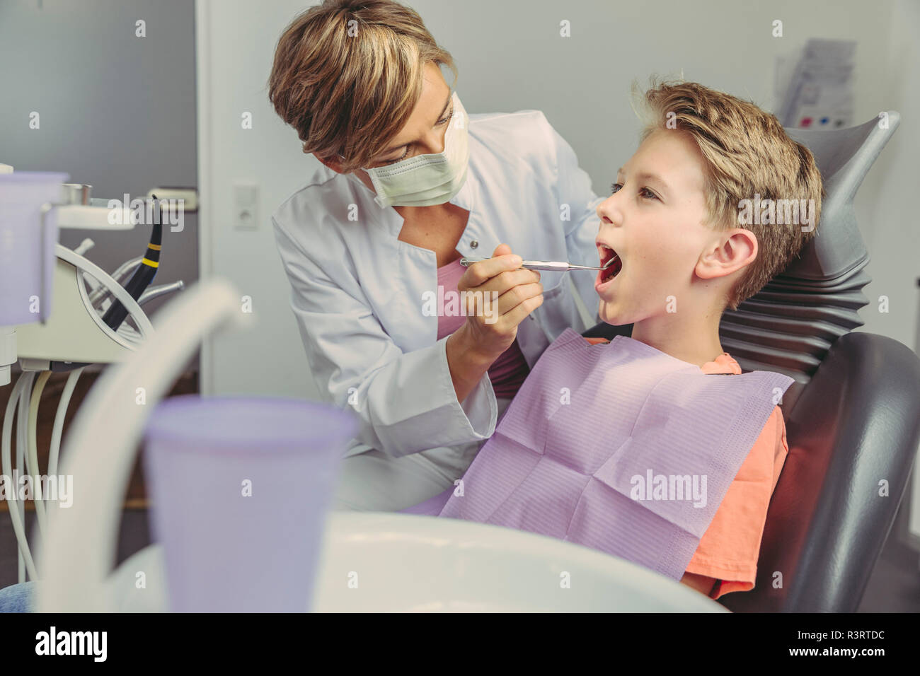 Dentista esaminando boy i denti con strumenti dentali Foto Stock