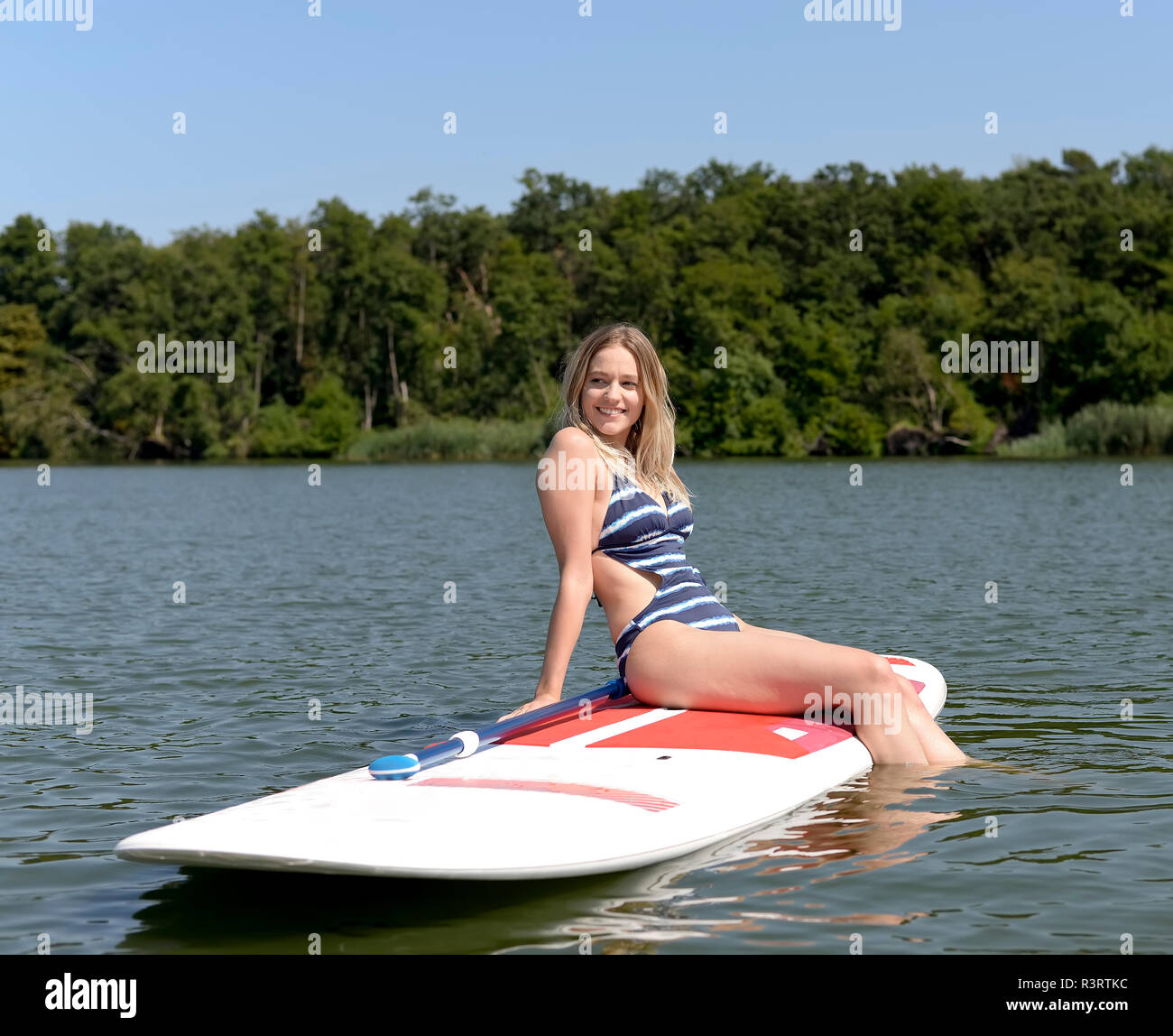 La Germania, il Land Brandeburgo, ritratto di sorridere giovane donna relax su paddleboard su Zeuthener vedere Foto Stock