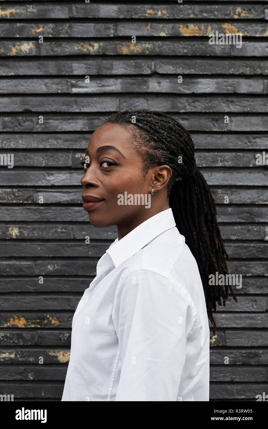 Ritratto di sorridere imprenditrice con dreadlocks che indossa una camicia bianca Foto Stock