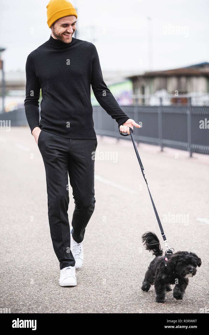 Moda giovane uomo a camminare con il cane su un ponte Foto Stock