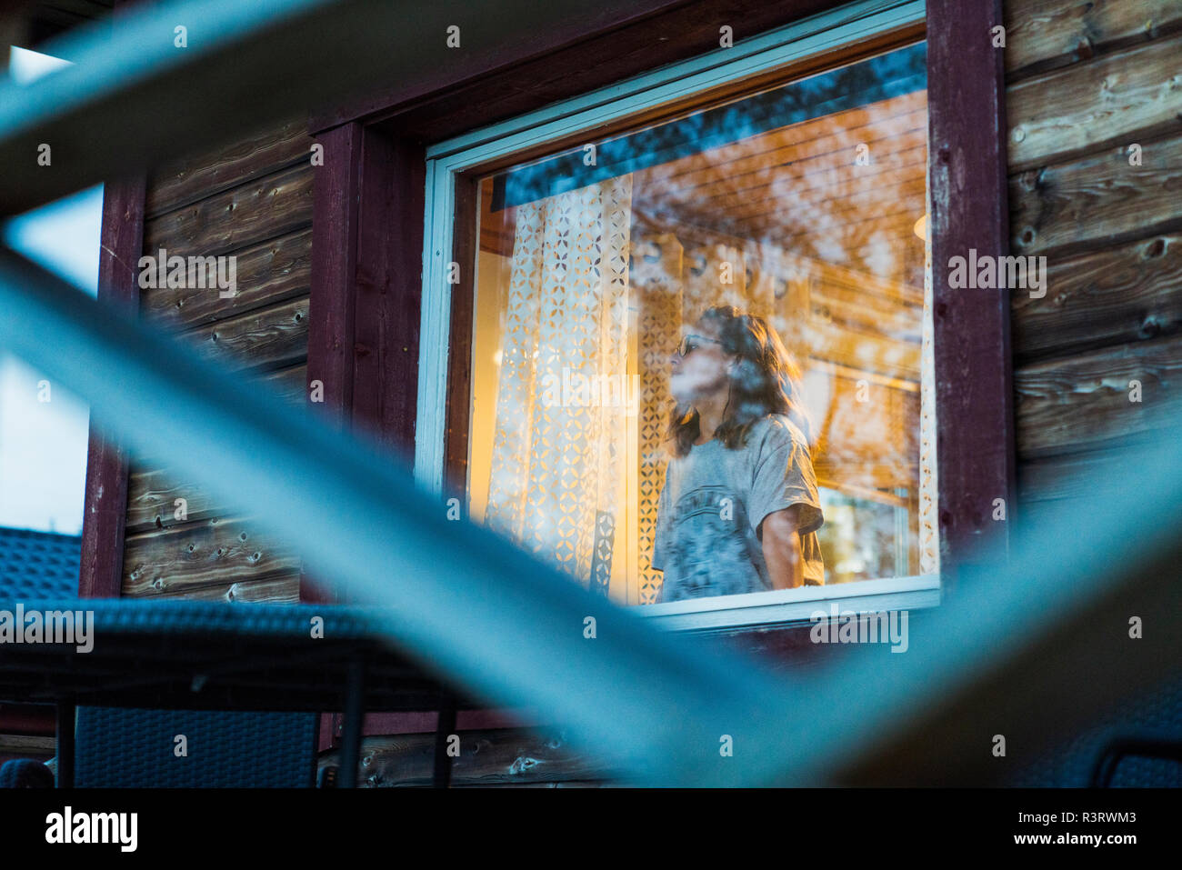 Giovane donna guardando fuori della finestra Foto Stock