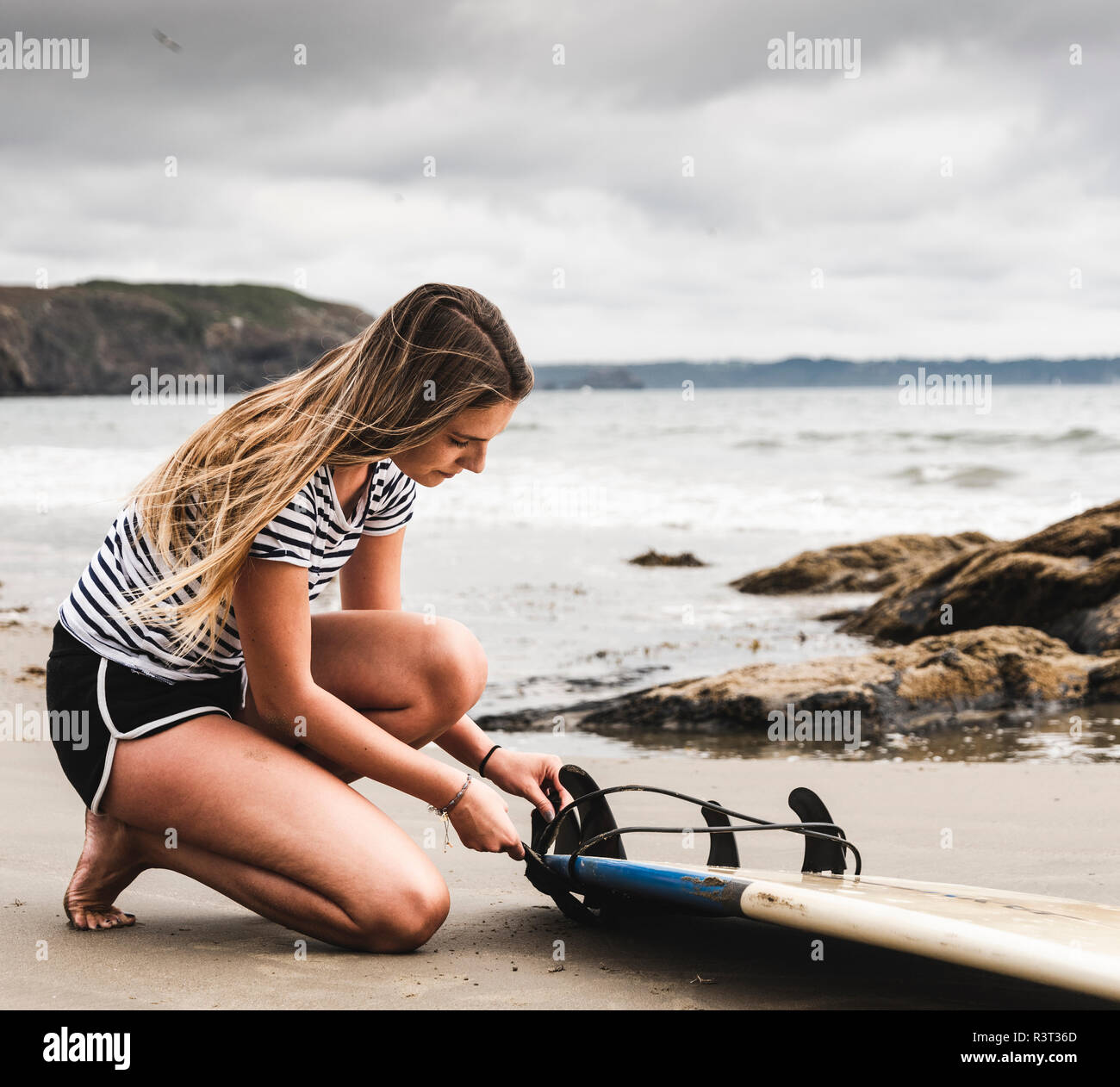 Giovane donna alla spiaggia la preparazione di tavole da surf Foto Stock