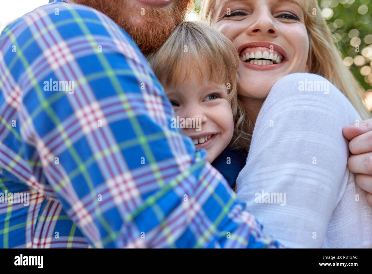 Genitori felici abbracciando la figlia all'aperto Foto Stock