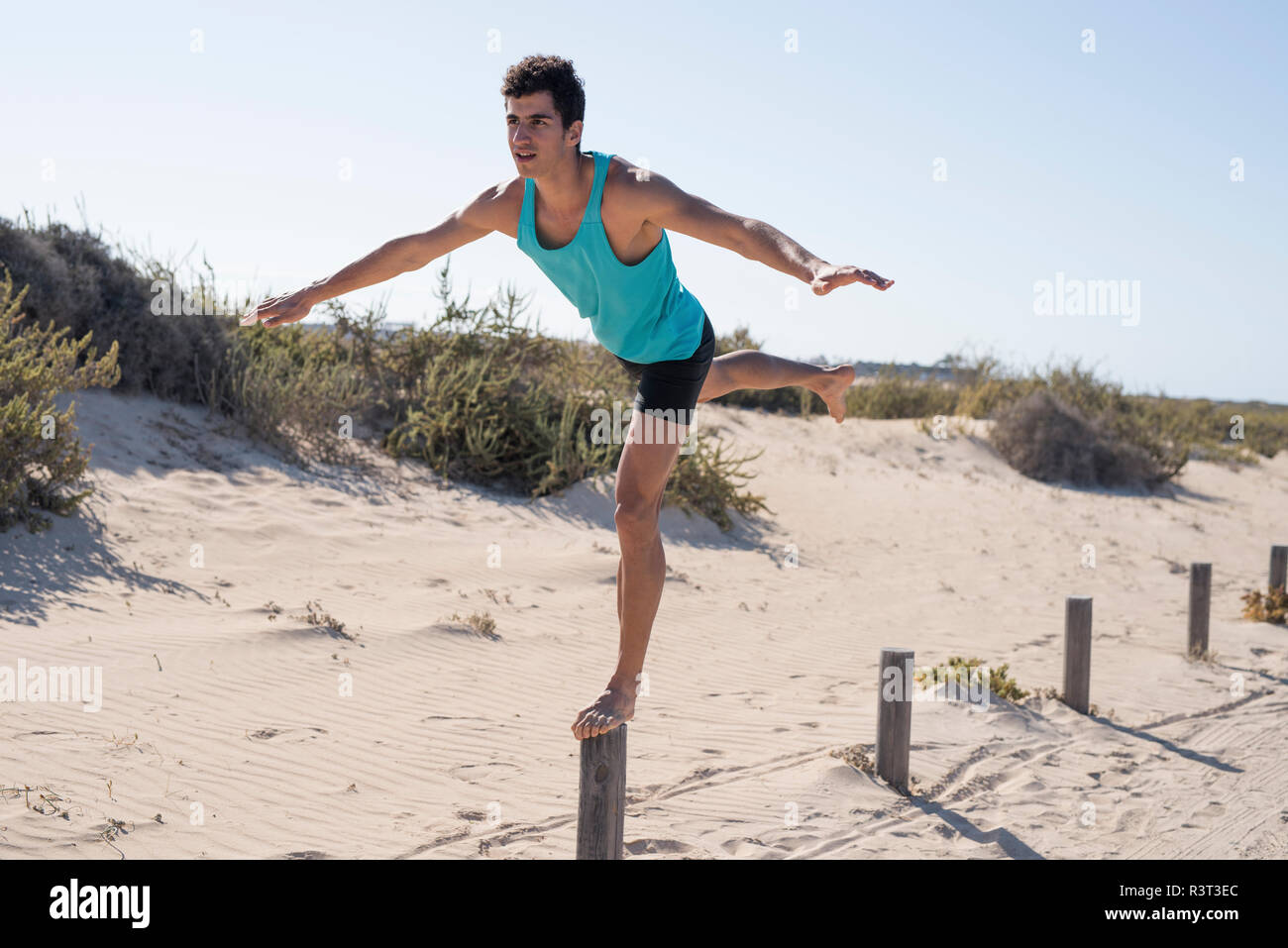 Spagna Isole Canarie Fuerteventura, giovane uomo che esercitano sulla spiaggia in equilibrio su un palo Foto Stock