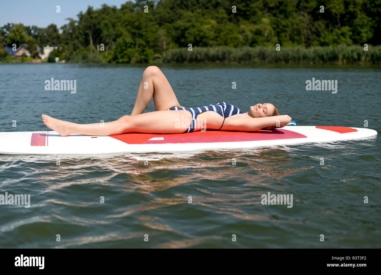 La Germania, il Land Brandeburgo, giovane donna relax su paddleboard su Zeuthener vedere Foto Stock