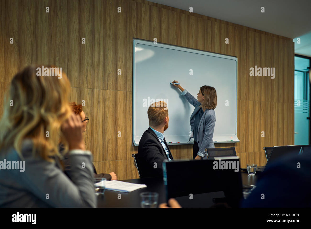 La gente di affari guardando imprenditrice iscritto su whiteboard Foto Stock