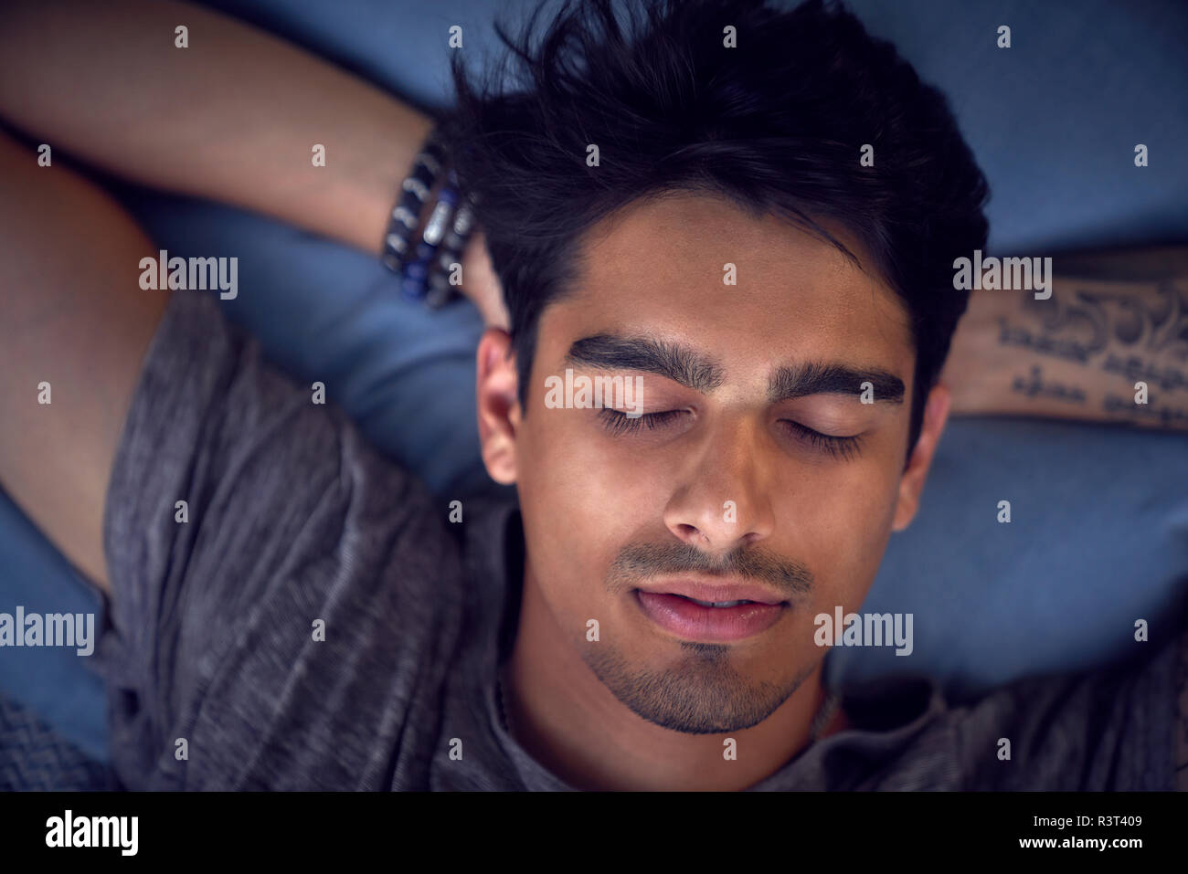Giovane uomo con tatuaggio, rilassante sul cuscino Foto Stock