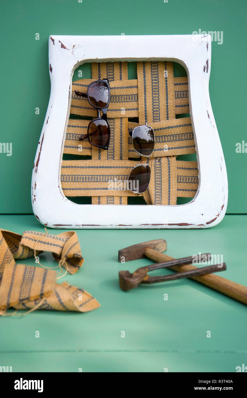 Pinza, martello, occhiali da sole appesi in superficie di seduta Foto Stock