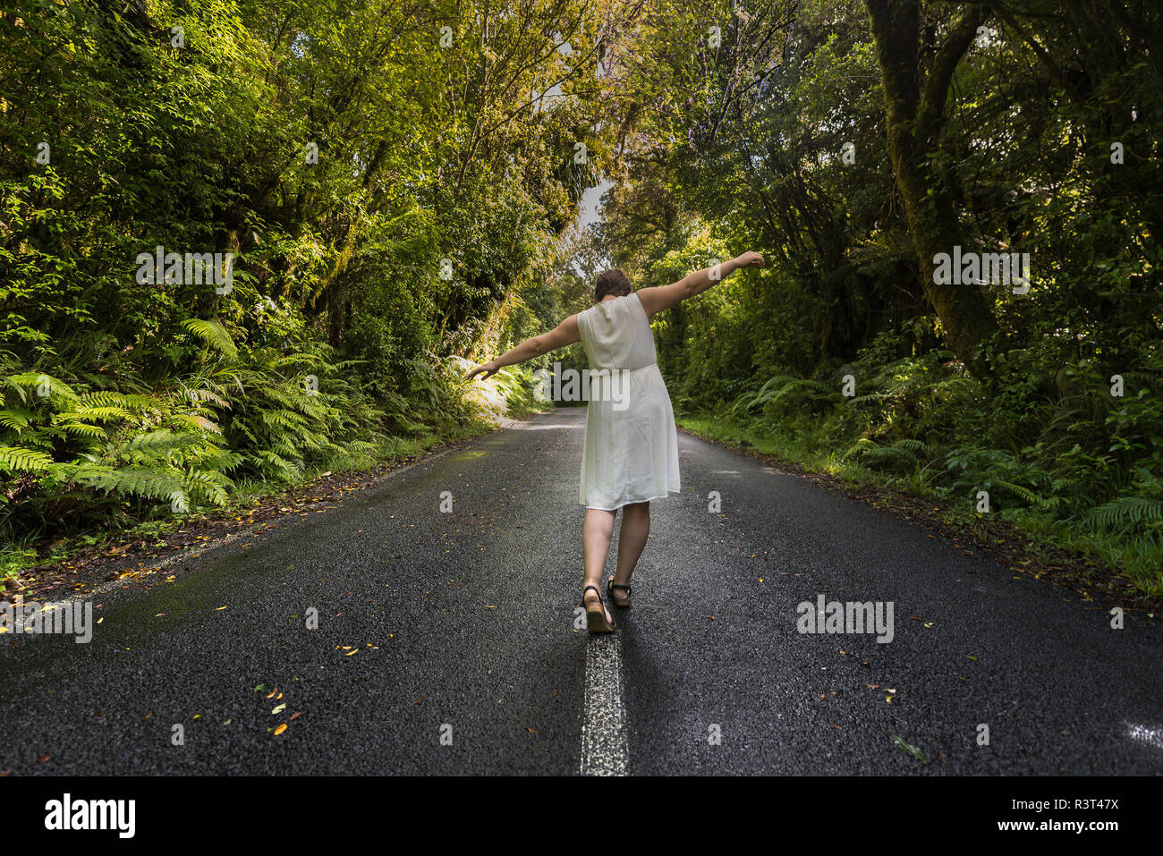 Nuova Zelanda, Isola del nord, Egmont National Park, Donna bilanciamento sulla linea centrale sulla strada Foto Stock