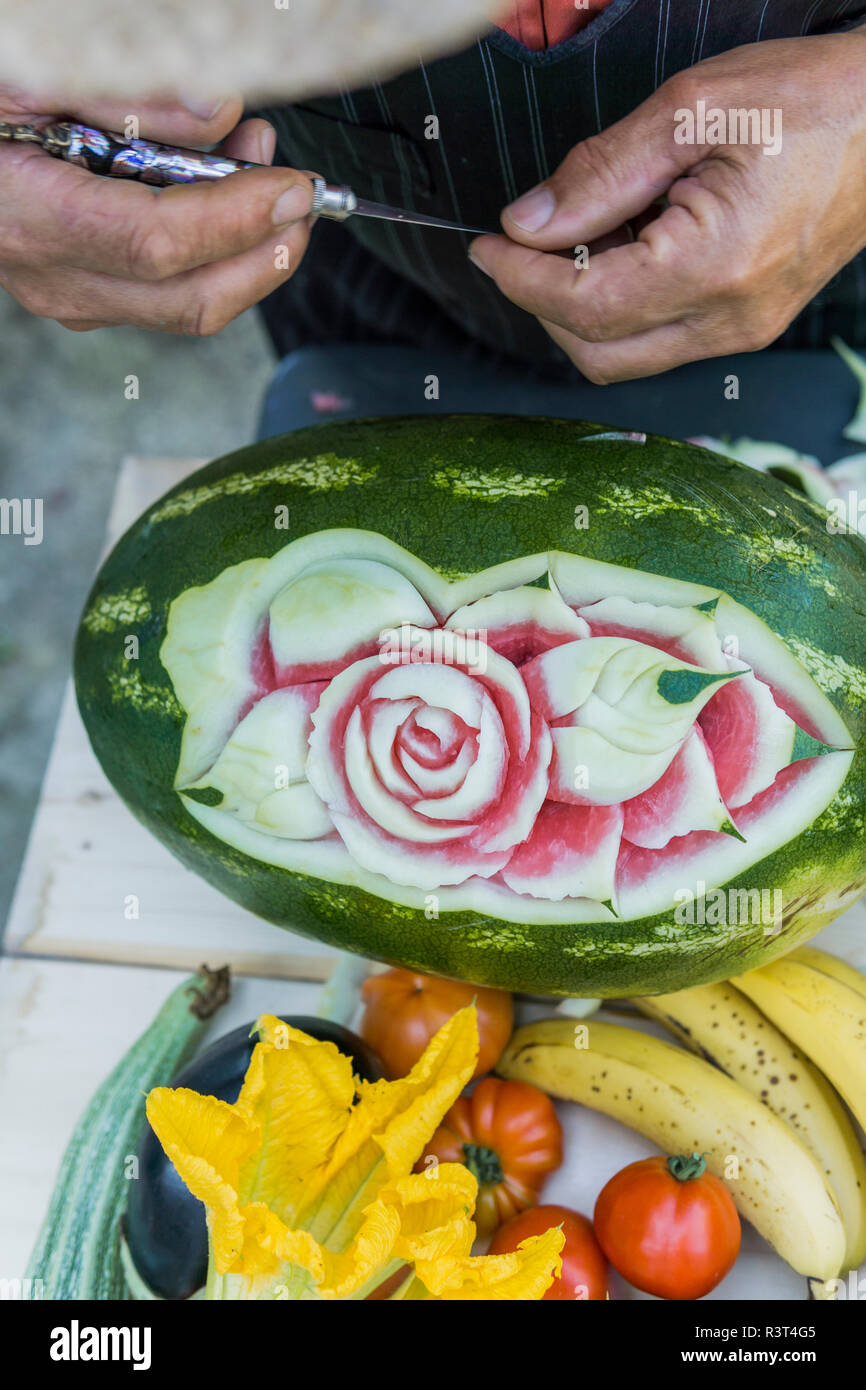 Close-up di uomo decorare un cocomero con carving tool Foto Stock