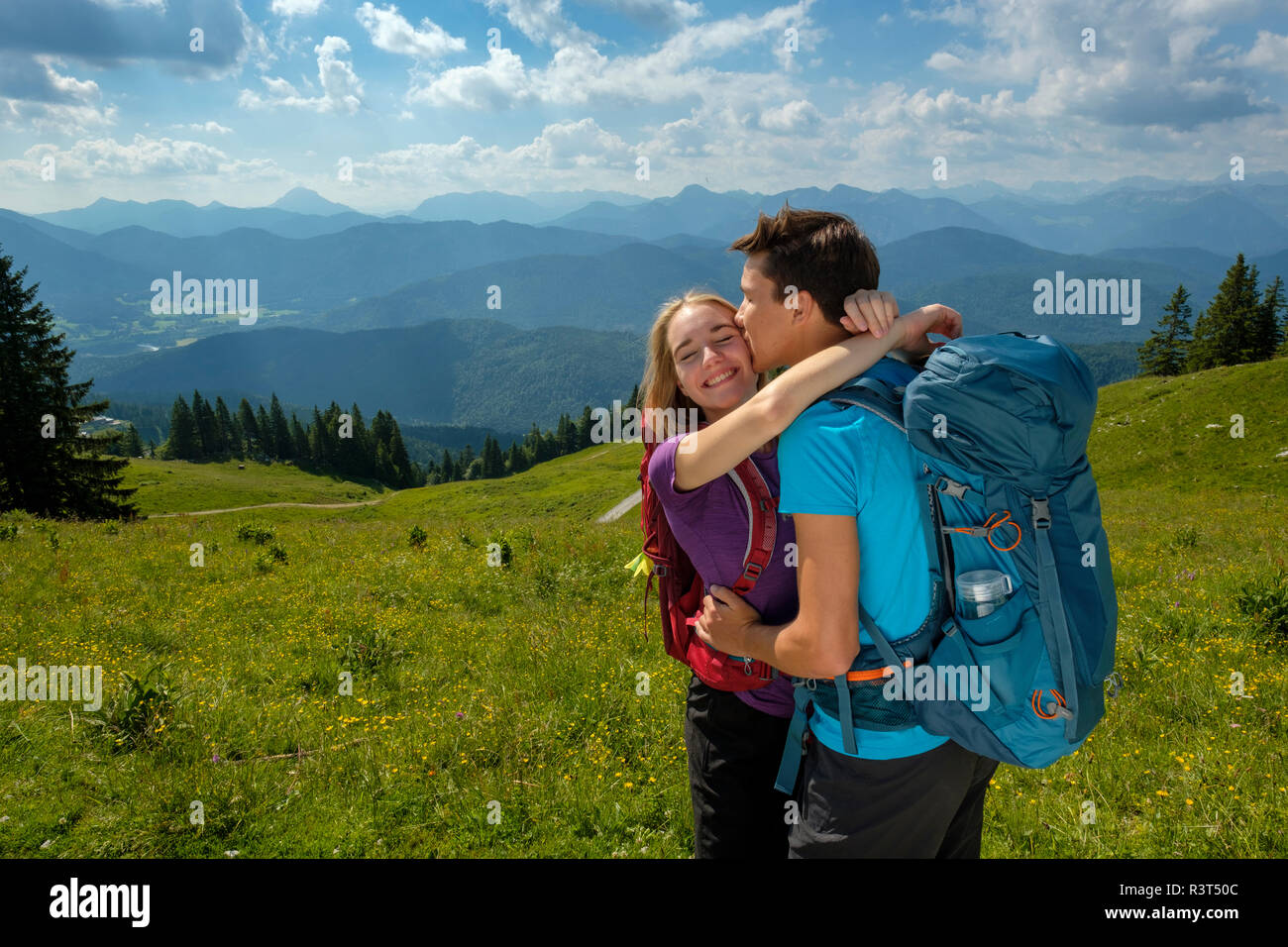 In Germania, in Baviera, vicino Brauneck Lenggries, felice coppia giovane abbracciando e baciando nel paesaggio alpino Foto Stock