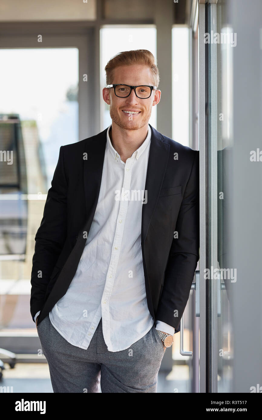 Ritratto di imprenditore sorridente in ufficio appoggiata contro la finestra Foto Stock