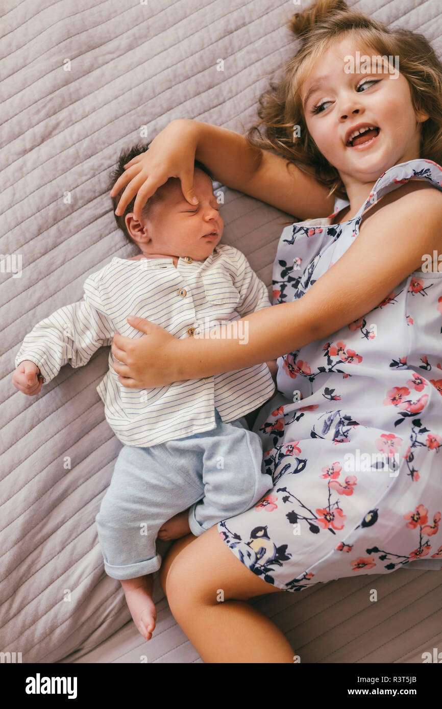 Giocoso ragazza distesa su una coperta coccole con il suo fratellino Foto Stock