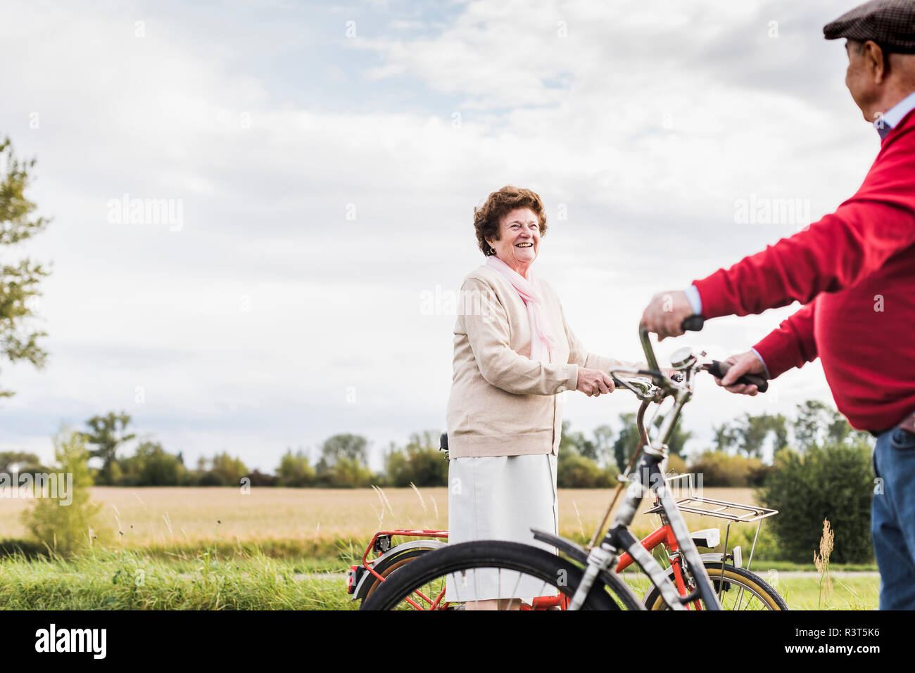 Senior l uomo e la donna con le biciclette incontro nel paesaggio rurale Foto Stock