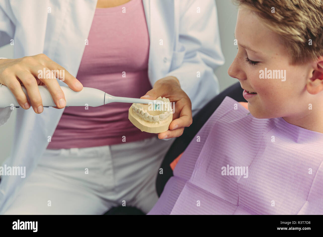 Dentista femmina ragazzo che spiega come pulire i suoi denti su un modello di denti Foto Stock