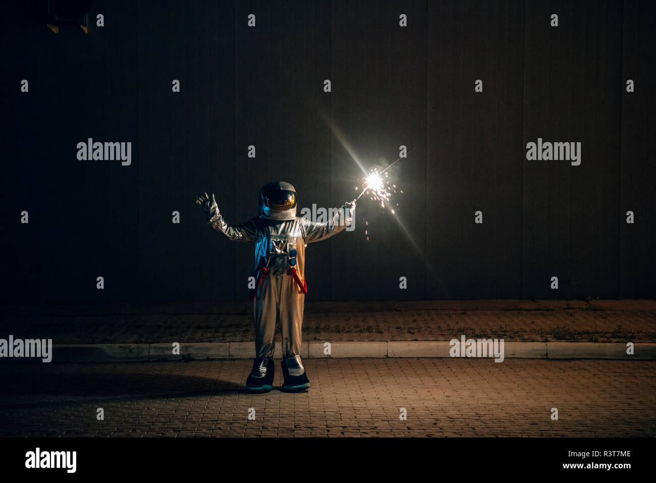 Spaceman in piedi su una strada di notte tenendo sparkler Foto Stock