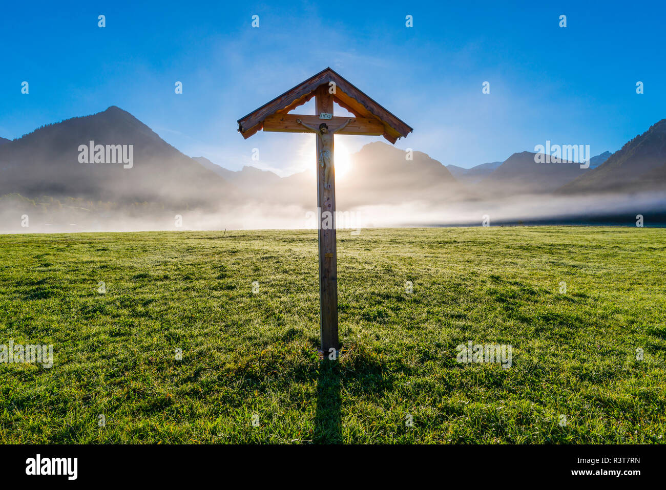 In Germania, in Baviera, Allgaeu, Allgaeu Alpi, Loretto prato vicino a Oberstdorf, campo croce contro sole al mattino Foto Stock