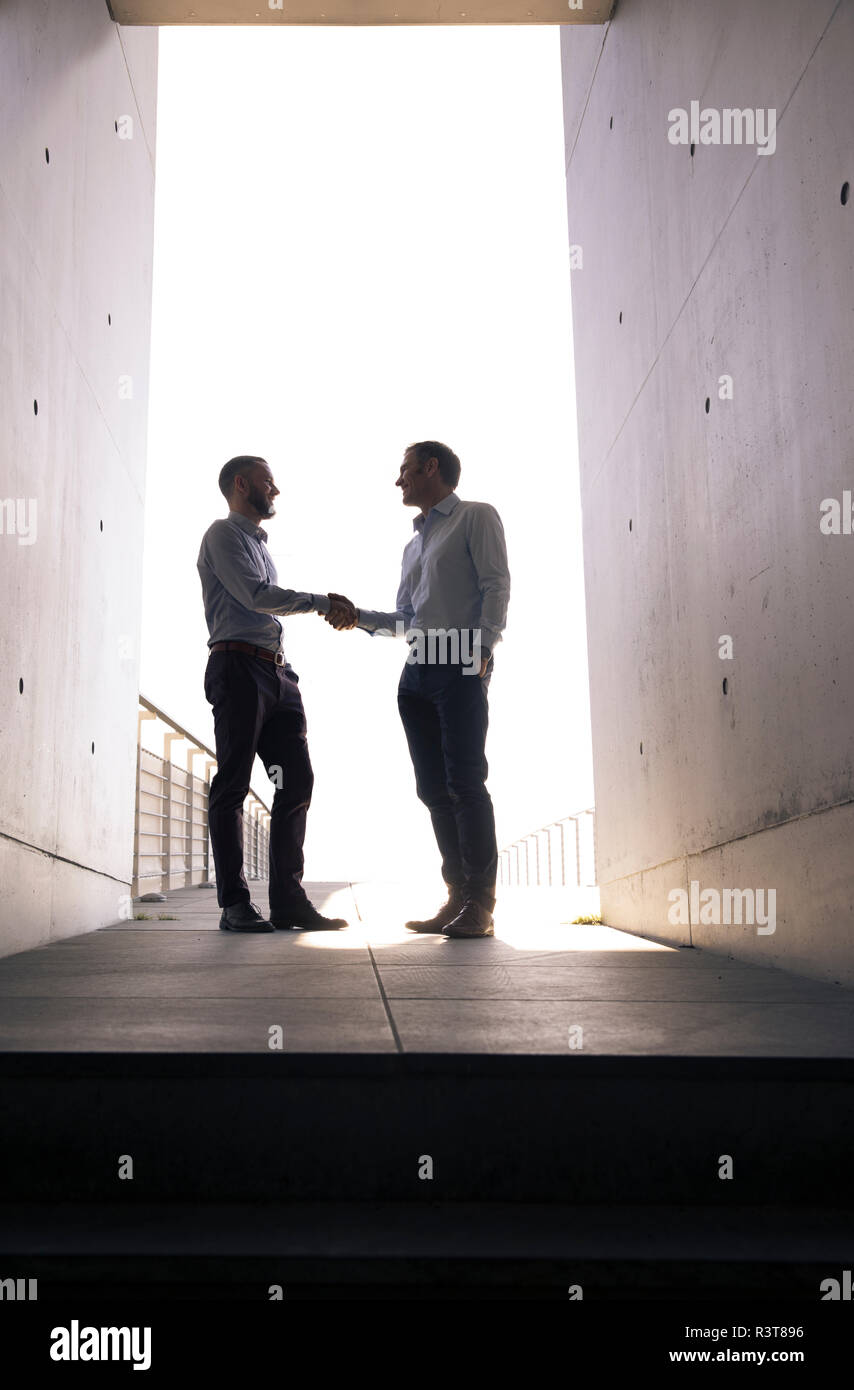 Due imprenditori stringono le mani in un passaggio Foto Stock