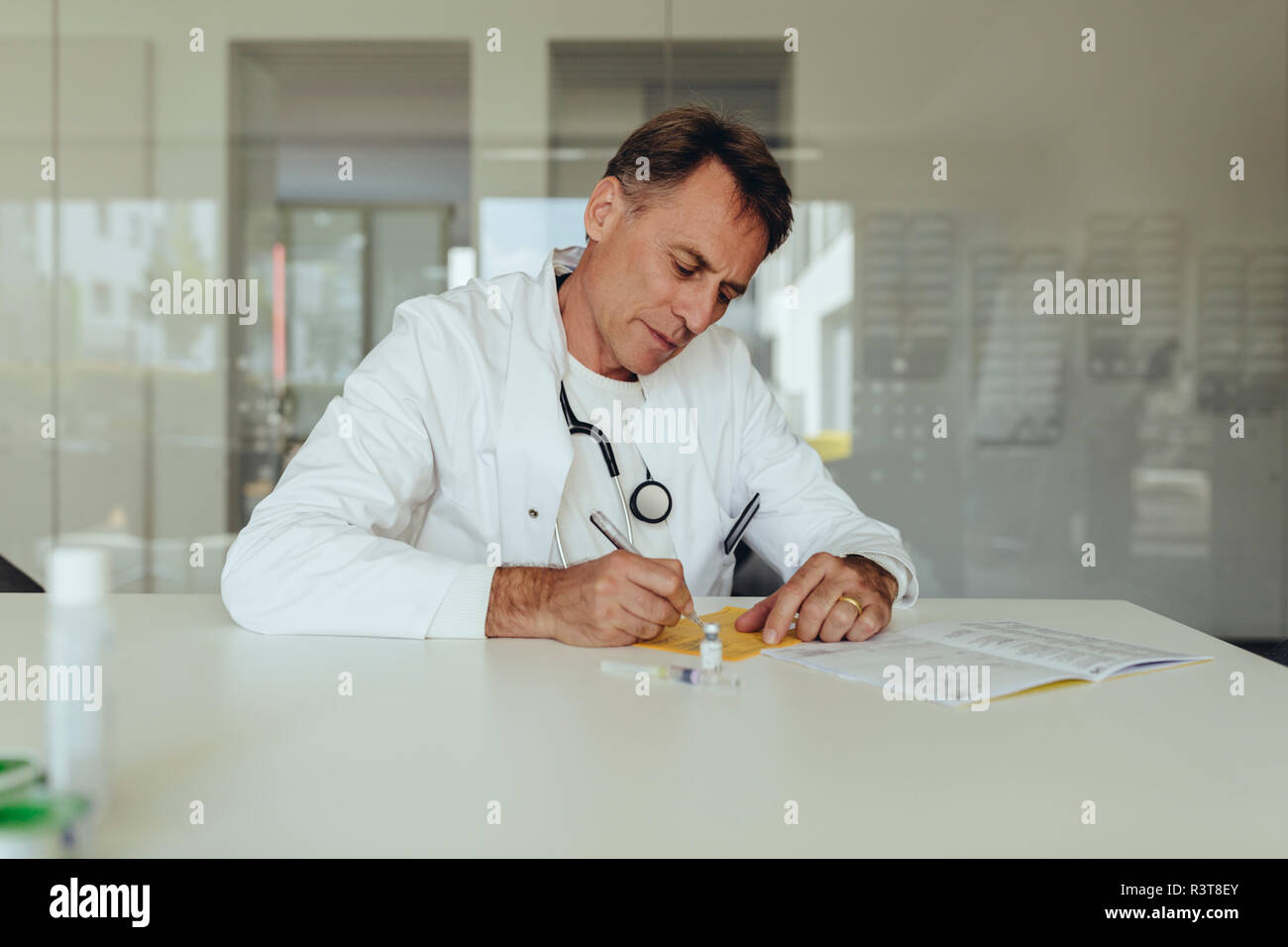 Medico seduta in pratica il riempimento nella scheda di immunizzazione Foto Stock