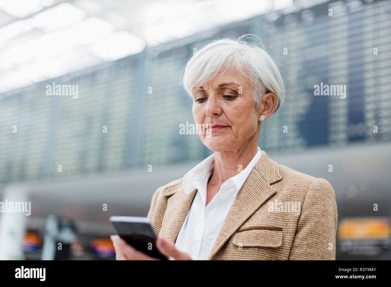 Senior imprenditrice tramite telefono cellulare presso l'aeroporto Foto Stock