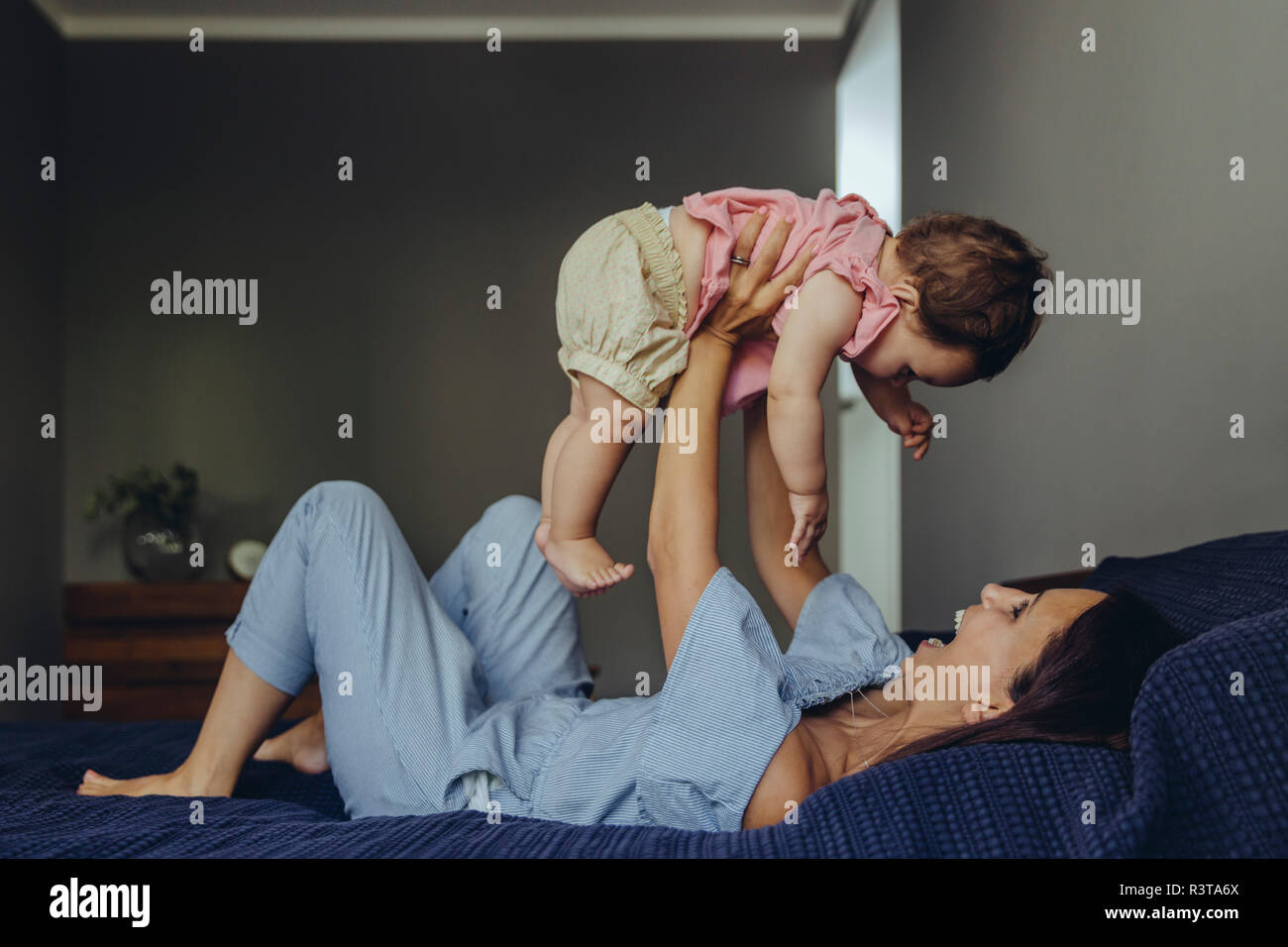 Felice madre solleva la sua bambina sul letto Foto Stock