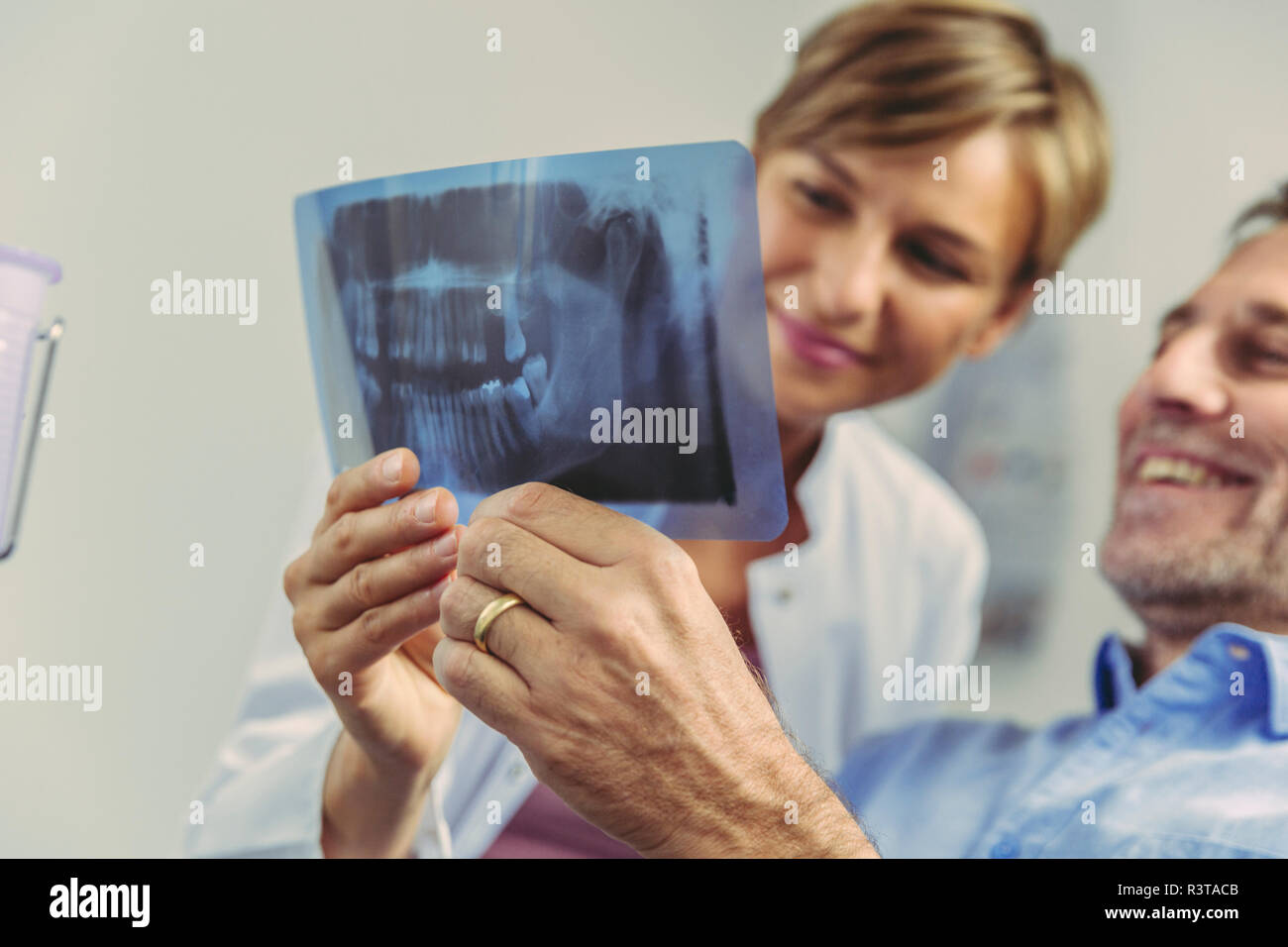 Dentista spiegando immagine a raggi x al paziente sorridente Foto Stock
