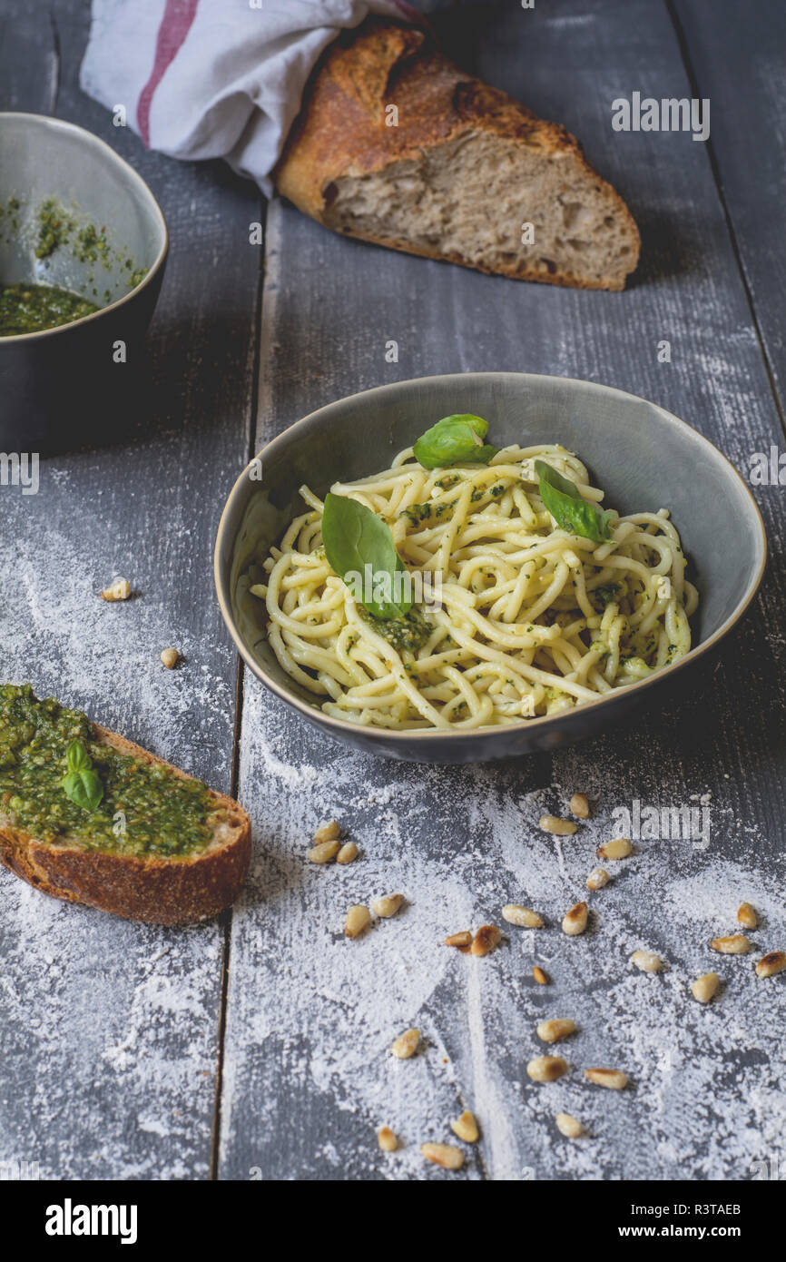 In casa pesto di basilico, spaghetti in una ciotola, segala baguette su legno Foto Stock