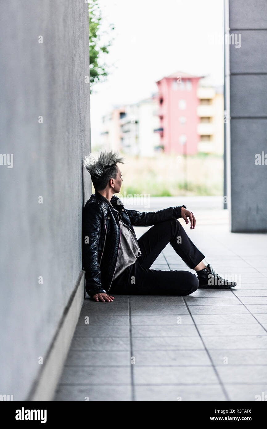Punk donna seduta a una parete Foto Stock
