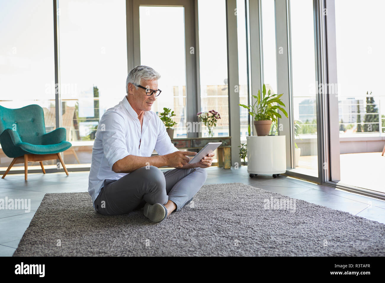 Coppia uomo seduto su un tappeto a casa utilizzando tablet Foto Stock