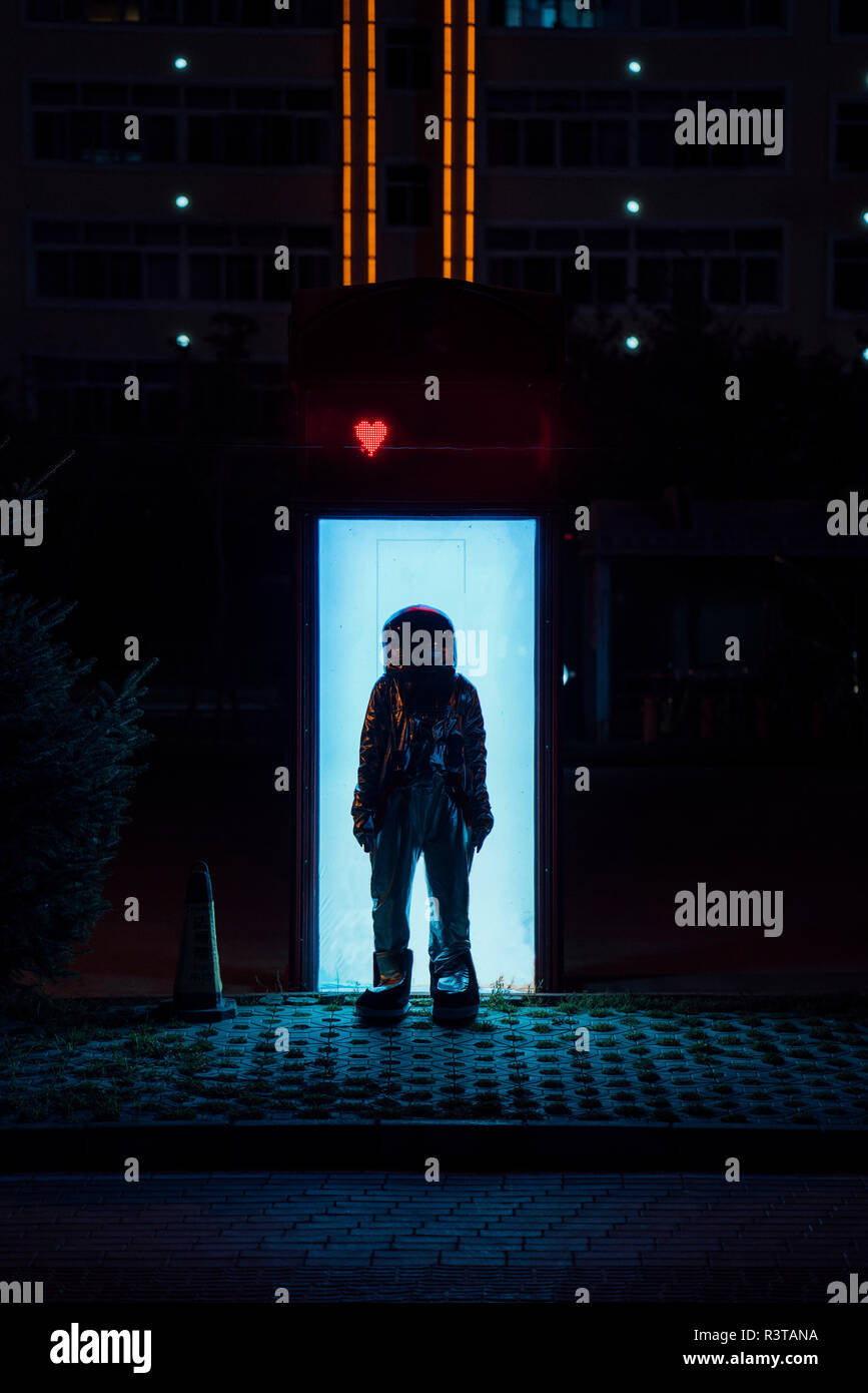 Spaceman in piedi in una scatola illuminata di notte Foto Stock