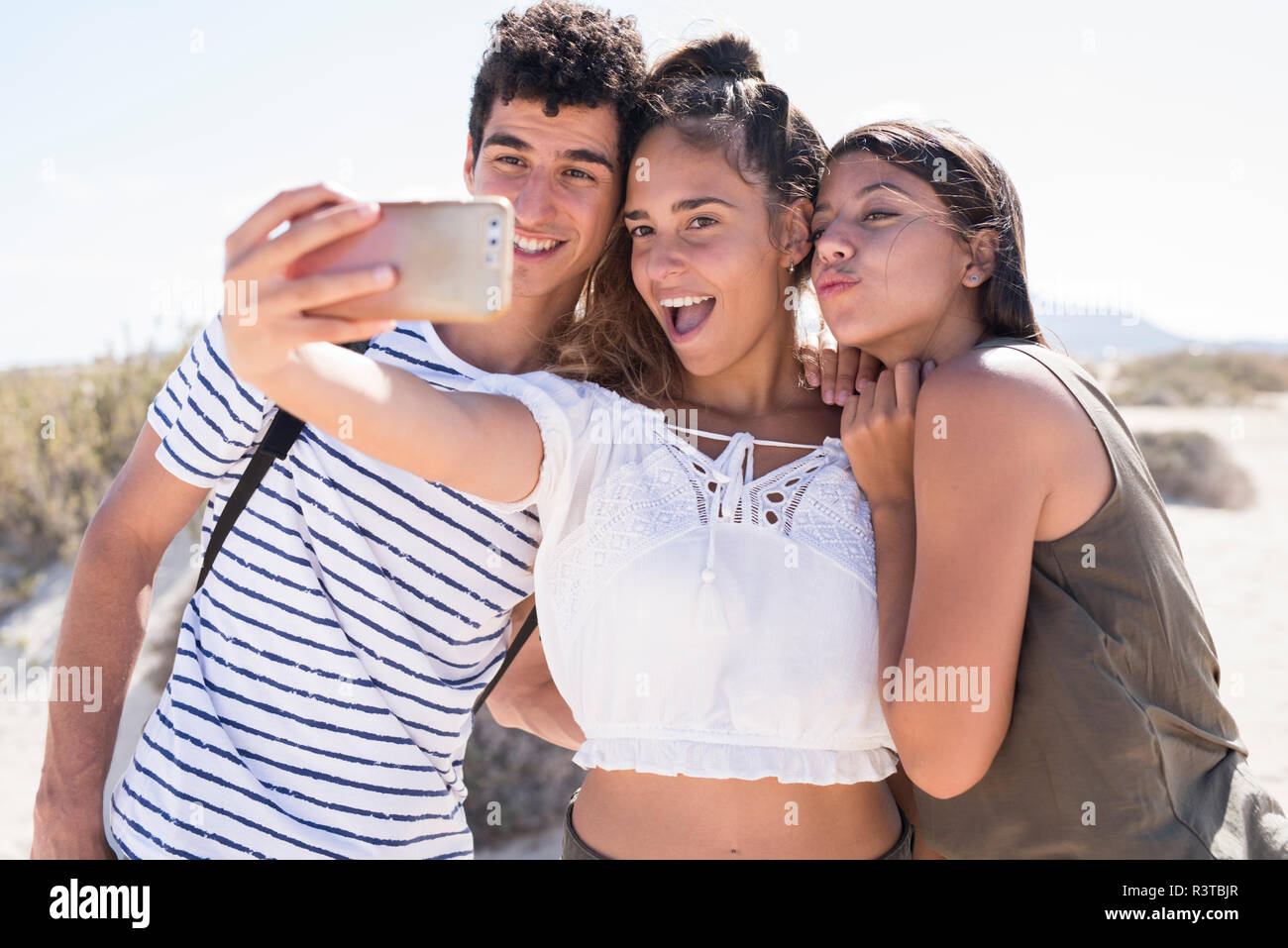 Amici divertendosi sulla spiaggia, tenendo selfies dello smartphone Foto Stock