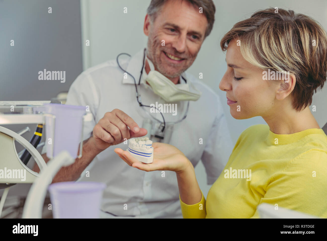 Dentista spiegando bridg dentale su un modello di denti per il suo paziente Foto Stock