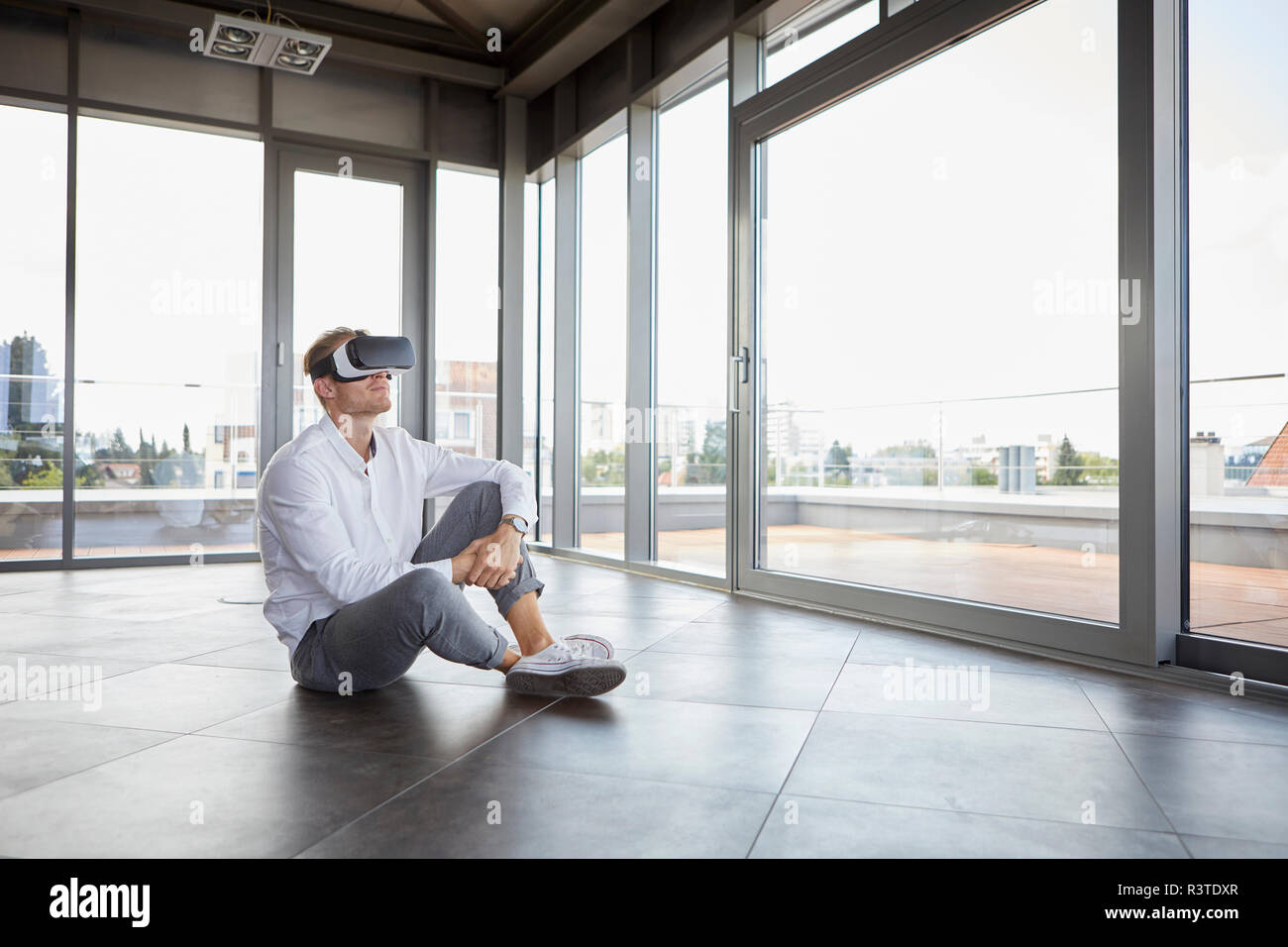 Imprenditore seduta nella stanza vuota indossando occhiali VR Foto Stock