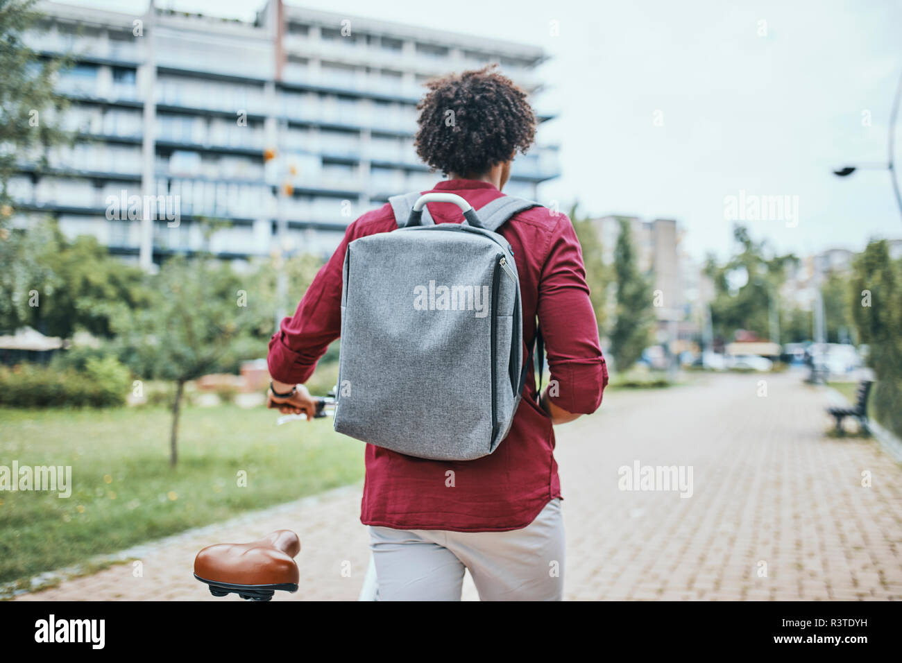 Giovane con zaino bicicletta di spinta in posizione di parcheggio Foto Stock