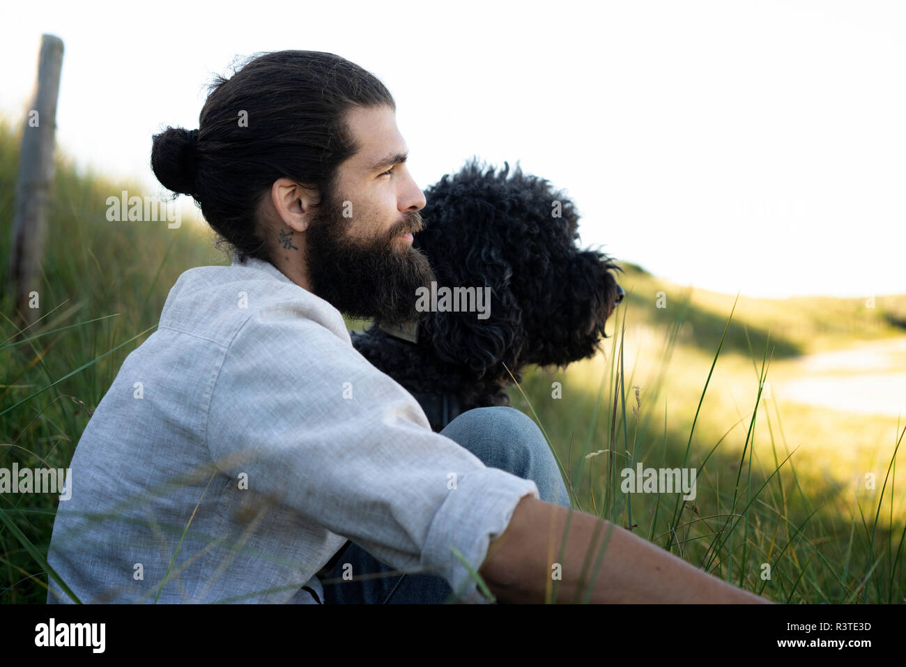 Giovane uomo seduto nelle dune con il suo cane Foto Stock